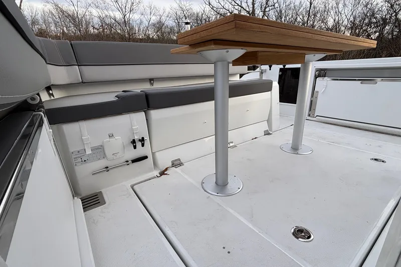 Slide: The Image of 2022 Jeanneau Leader 9.0 CC boat interior with wooden table and cushioned seating. - 4