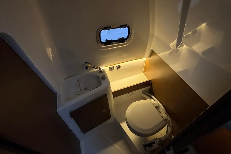 Slide: The Image of 2022 Jeanneau Leader 9.0 CC boat bathroom with sink, toilet, and porthole window. - 42