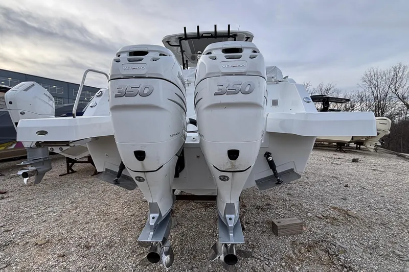 Slide: The Image of 2022 Jeanneau Leader 9.0 CC with twin 350 horsepower outboard engines, parked on gravel. - 49