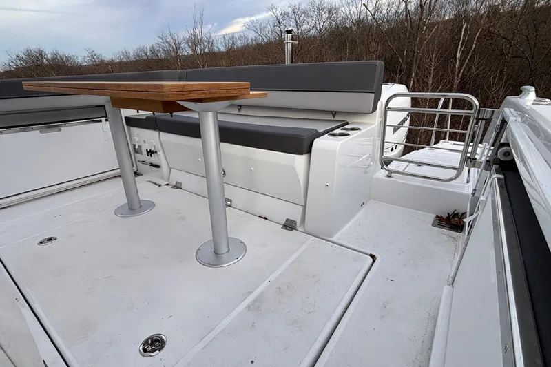 Slide: The Image of 2022 Jeanneau Leader 9.0 CC boat deck with seating and table, surrounded by trees. - 5