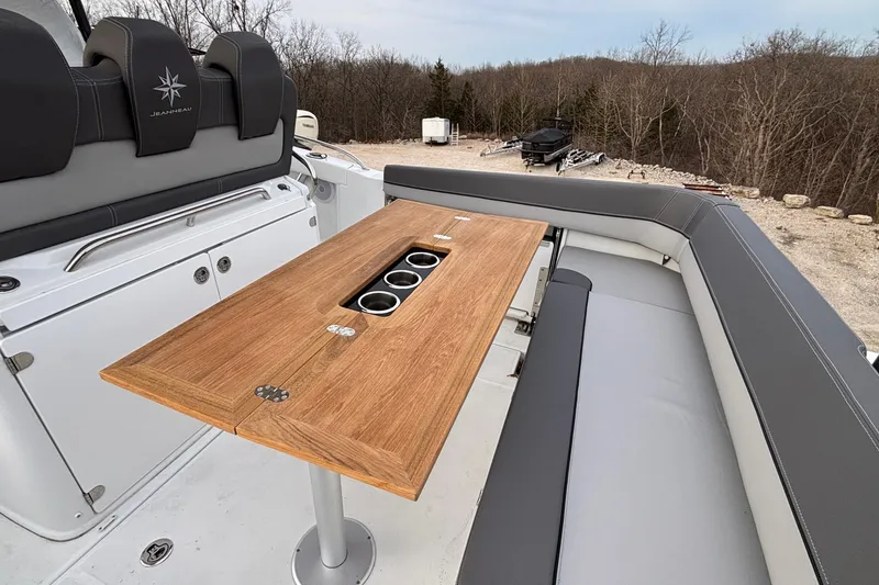 Slide: The Image of 2022 Jeanneau Leader 9.0 CC boat interior with wooden table and cushioned seating. - 9