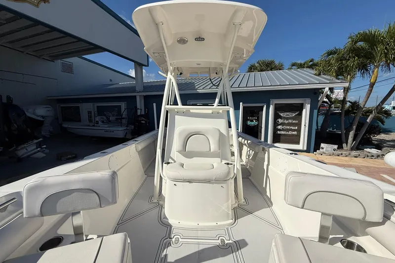 Slide: The Image of 2022 Sea Born LX24 Center Console boat with T-top, docked near a marine shop. - 29
