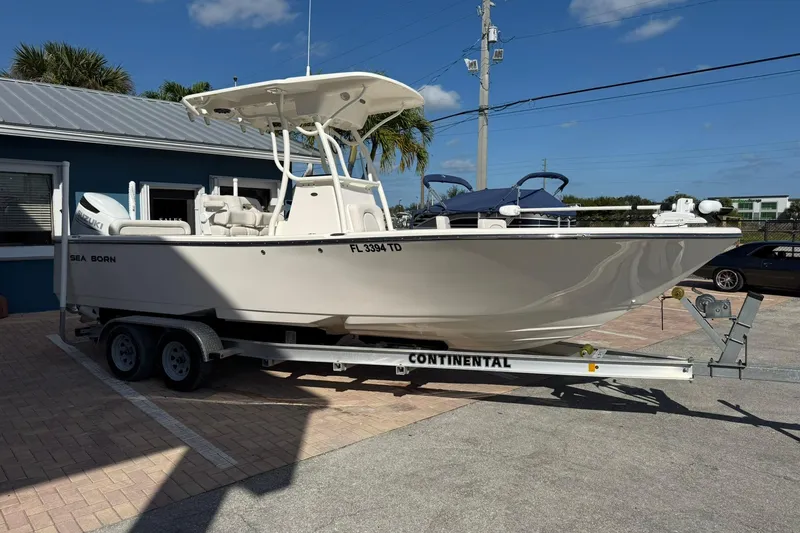 Slide: The Image of 2022 Sea Born LX24 Center Console boat on trailer, parked outdoors under clear sky. - 5