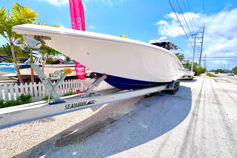 Slide: The Image of 2023 Fountain 38 Center Console boat on trailer, parked roadside under clear sky. - 5
