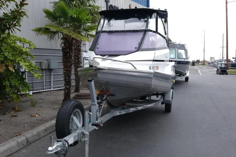 Slide: The Image of 2019 Stabicraft 1550 Fisher boat on trailer, parked near palm tree and building. - 3
