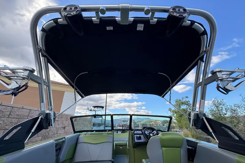 Slide: The Image of 2023 MasterCraft NXT22 boat interior with canopy and seating, under a partly cloudy sky. - 10