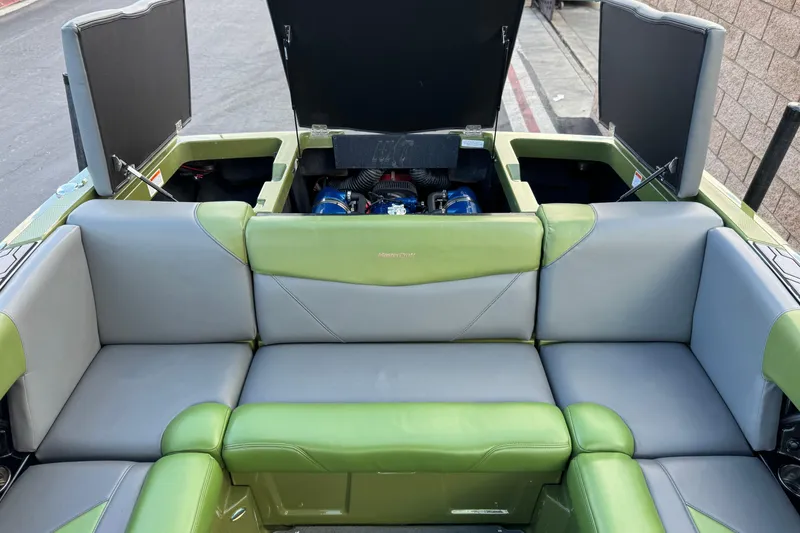 Slide: The Image of 2023 MasterCraft NXT22 boat interior with green and gray seating, open engine compartments. - 19