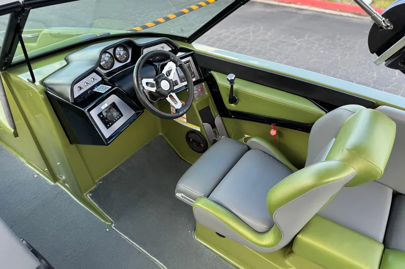 Slide: The Image of 2023 MasterCraft NXT22 boat interior with green and gray seating, modern dashboard, and steering wheel. - 27
