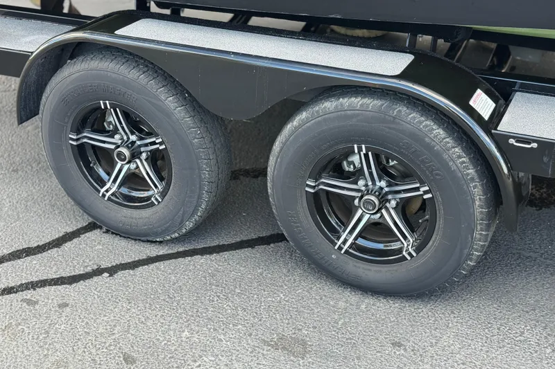 Slide: The Image of 2023 MasterCraft NXT22 trailer with black alloy wheels on a textured surface. - 33