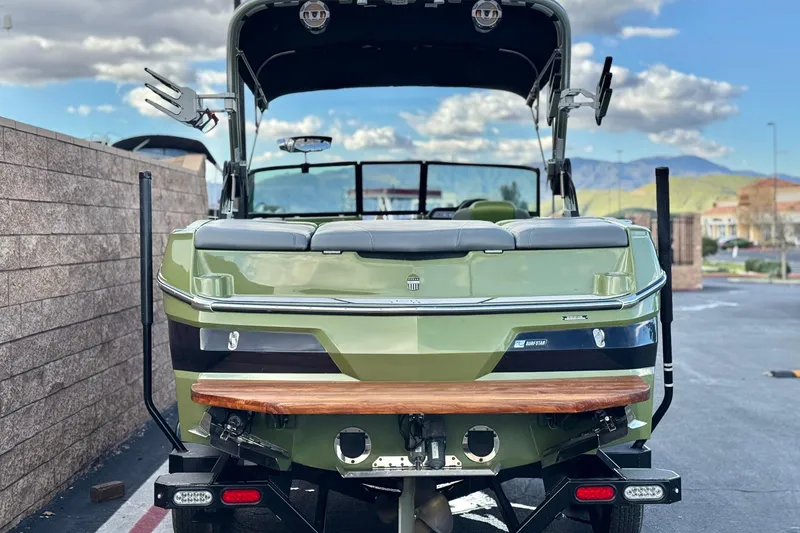Slide: The Image of 2023 MasterCraft NXT22 boat, rear view, parked outdoors with mountains in background. - 4