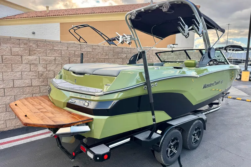 Slide: The Image of 2023 MasterCraft NXT22 boat on trailer, green and black design, with wakeboard tower. - 5