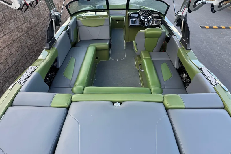 Slide: The Image of 2023 MasterCraft NXT22 boat interior with green and gray seating, modern dashboard. - 9