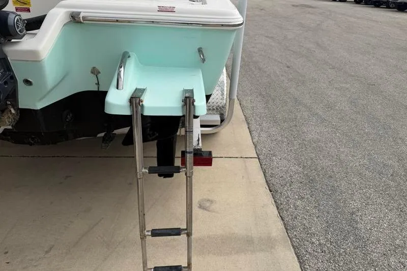 Slide: The Image of 2024 Key West 210 Bay Reef boat with a foldable swim ladder on a concrete surface. - 17