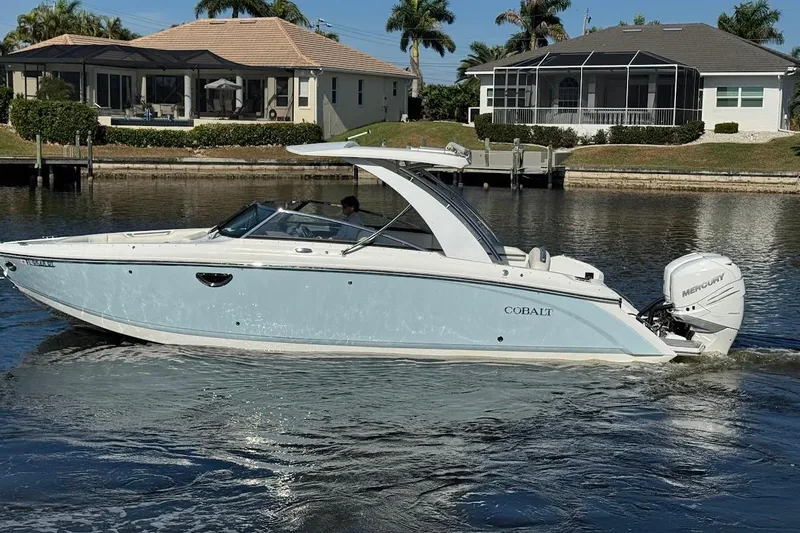 Slide: The Image of 2018 Cobalt 30SC boat cruising on a calm waterway near waterfront homes. - 11