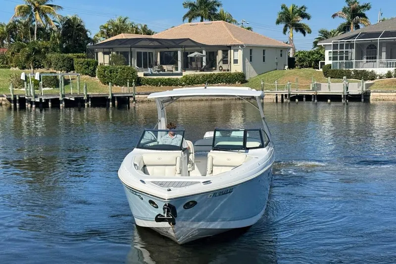 Slide: The Image of 2018 Cobalt 30SC boat cruising on a sunny waterfront with houses and palm trees. - 13