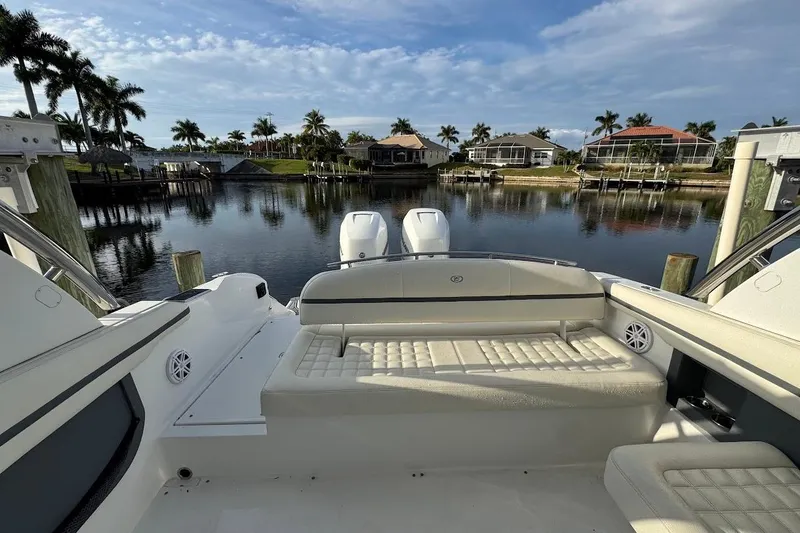 Slide: The Image of 2018 Cobalt 30SC boat with luxurious seating, docked by a scenic waterfront with palm trees. - 17