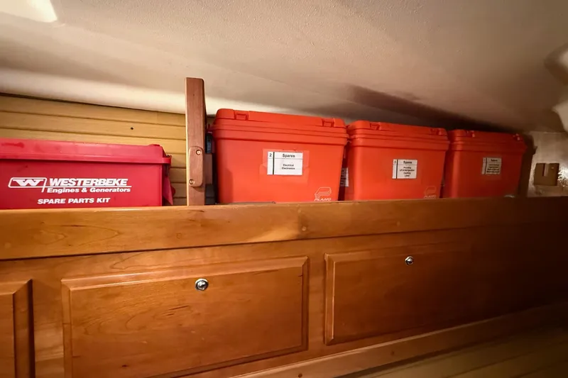 Slide: The Image of Storage area with labeled orange containers and a red spare parts kit on a Sabre 362, 2003 model. - 23