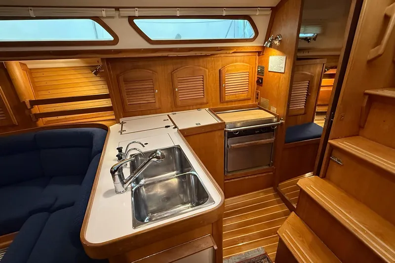 Slide: The Image of 2003 Sabre 362 yacht interior with wooden cabinetry, stainless steel sink, and compact kitchen area. - 4