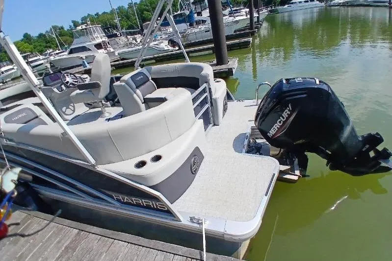 Slide: The Image of 2024 Harris HCX23 pontoon boat docked, featuring a Mercury outboard motor. - 10