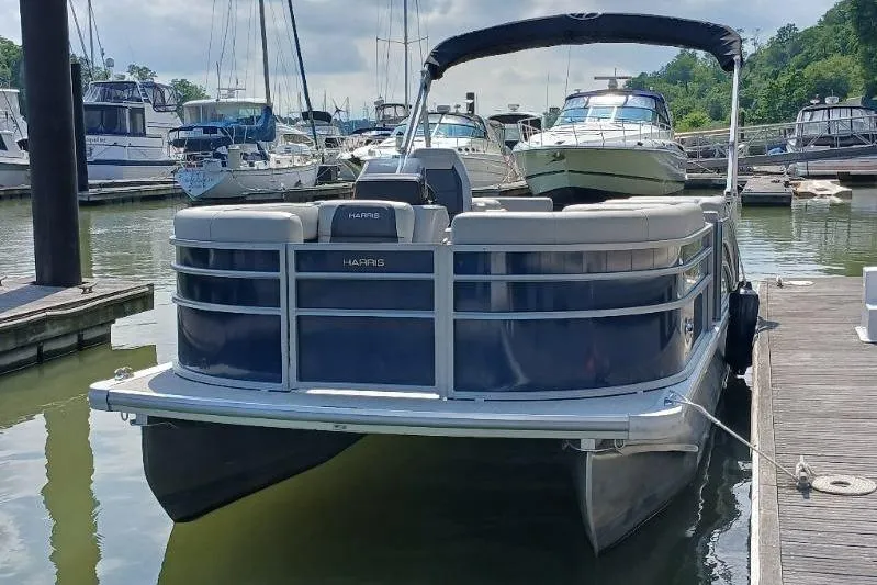 Slide: The Image of 2024 Harris HCX23 pontoon boat docked at marina with other boats. - 3