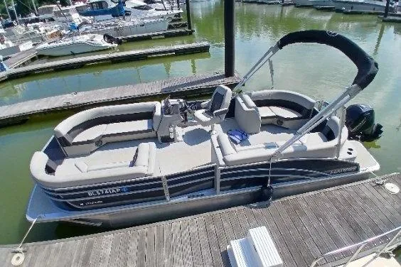 Slide: The Image of 2024 Harris HCX23 pontoon boat docked at marina, featuring spacious seating and modern design. - 4