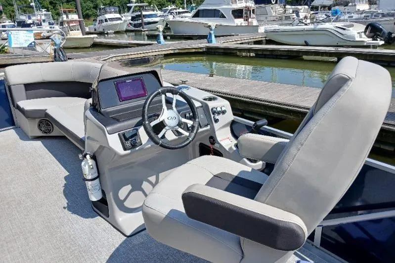 Slide: The Image of 2024 Harris HCX23 boat interior with steering wheel and seating at marina. - 5