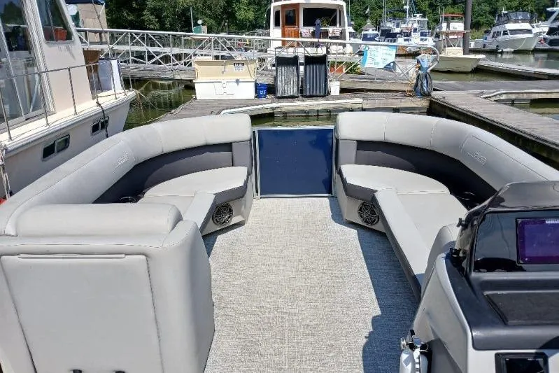 Slide: The Image of 2024 Harris HCX23 pontoon boat interior with gray seating at a marina. - 6