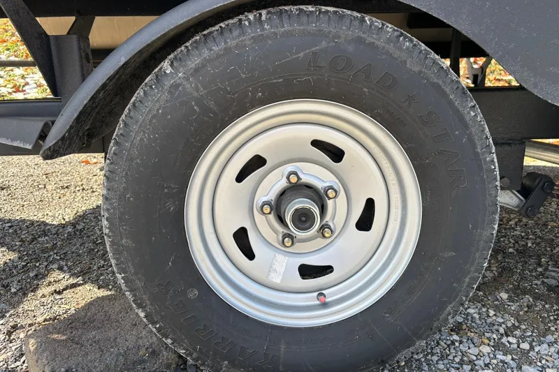 Slide: The Image of Trailer wheel of 2023 Sun Tracker Fishin' Barge 20 DLX on gravel surface. - 21