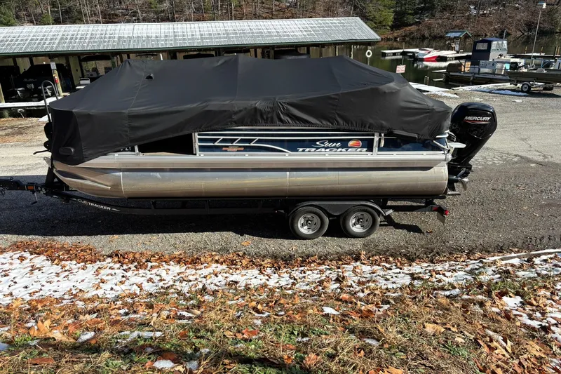 Slide: The Image of 2023 Sun Tracker Fishin' Barge 20 DLX pontoon boat covered, on trailer, near marina. - 22