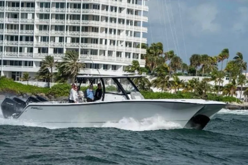 Slide: The Image of 2024 Front Runner 37 Catamaran cruising near a coastal building with palm trees. - 109