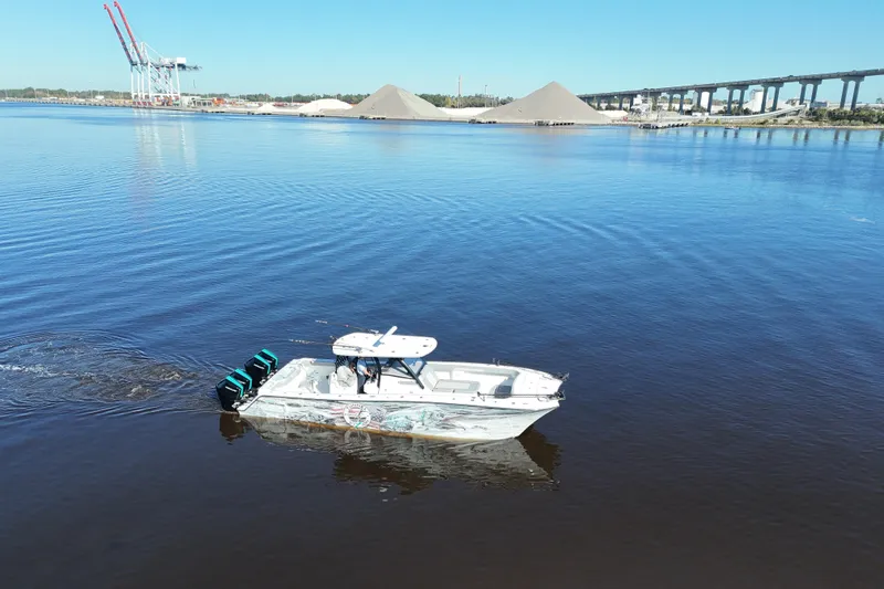 Slide: The Image of 2024 Front Runner 37 Catamaran cruising on a calm river with industrial backdrop. - 42