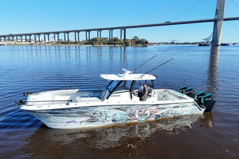Slide: The Image of 2024 Front Runner 37 Catamaran on water near bridge, featuring fishing rods and custom graphics. - 44