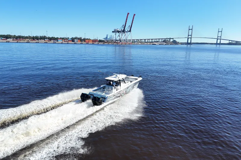 Slide: The Image of 2024 Front Runner 37 Catamaran cruising on a river near a bridge and port. - 75