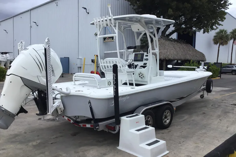 Slide: The Image of 2020 Yellowfin 24 Bay CE boat on trailer, parked near a warehouse. - 2