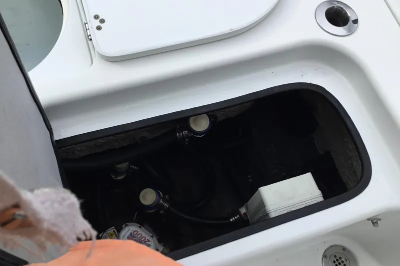 Slide: The Image of 2020 Yellowfin 24 Bay CE boat compartment with visible plumbing and wiring. - 24