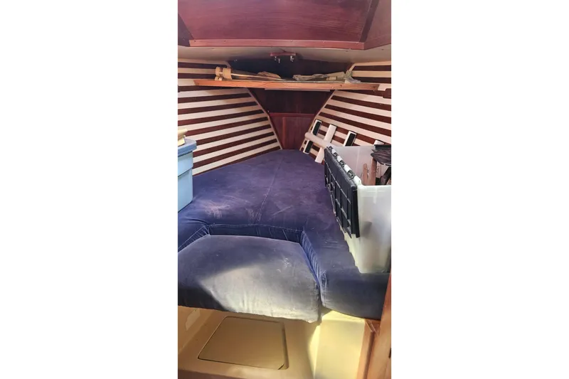 Slide: The Image of 1984 Endeavour 33 sailboat interior with striped wood paneling and blue cushioned berth. - 19