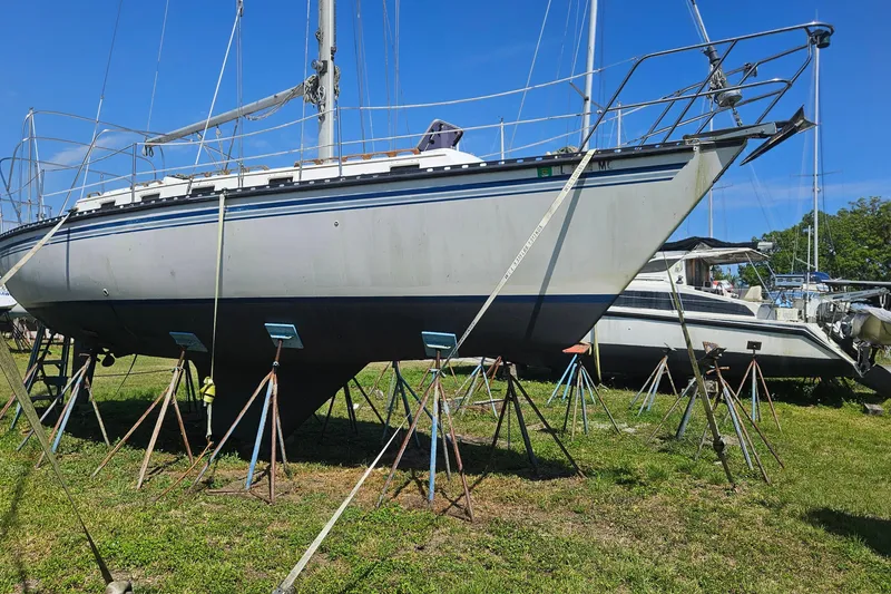 Slide: The Image of 1984 Endeavour 33 sailboat on stands in a grassy boatyard under clear blue sky. - 2