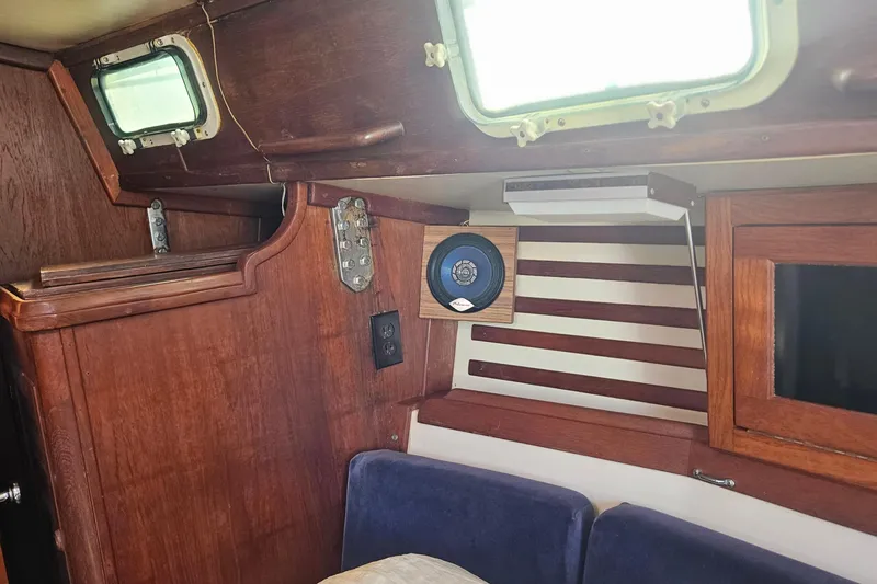 Slide: The Image of Interior of a 1984 Endeavour 33 sailboat with wood paneling and porthole. - 22
