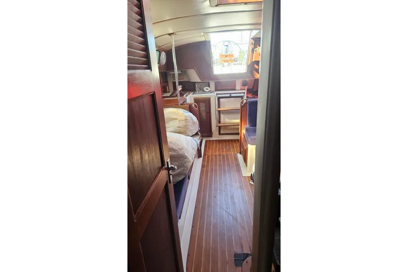 Slide: The Image of Interior of 1984 Endeavour 33 sailboat, featuring wooden flooring and cozy cabin space. - 24