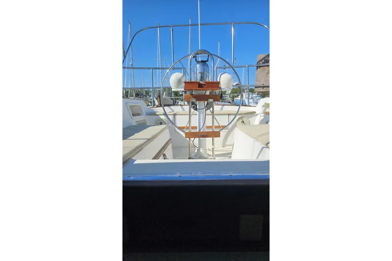 Slide: The Image of 1984 Endeavour 33 sailboat cockpit with steering wheel, docked in marina under clear blue sky. - 9