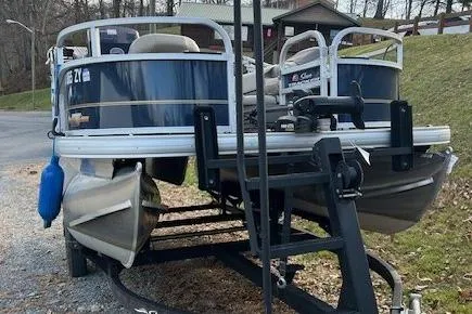 Slide: The Image of 2023 Sun Tracker Bass Buggy 16 XL Select pontoon boat on trailer, parked outdoors. - 3