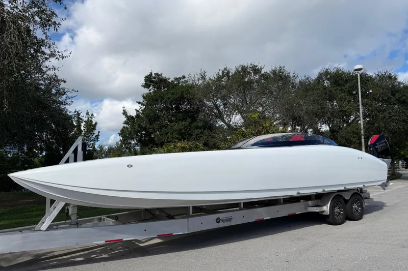 Slide: The Image of 2022 Doug Wright 320 powerboat on trailer, parked outdoors with trees in background. - 2