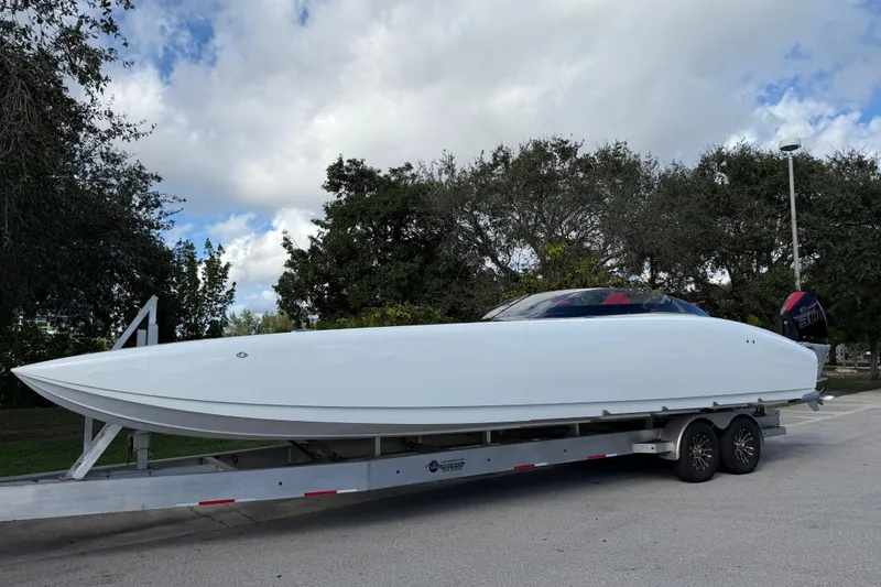 Slide: The Image of 2022 Doug Wright 320 powerboat on trailer, parked outdoors under cloudy sky. - 7