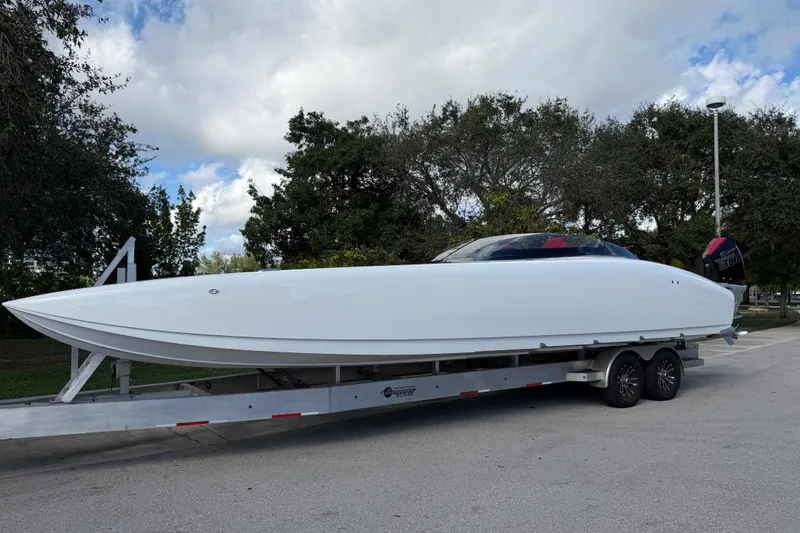 Slide: The Image of 2022 Doug Wright 320 powerboat on trailer, parked outdoors under cloudy sky. - 8