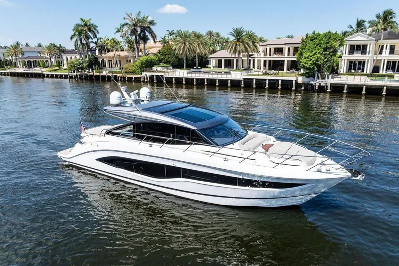 The Image of Luxury 2020 Princess V55 yacht cruising near waterfront homes, surrounded by palm trees. - 0
