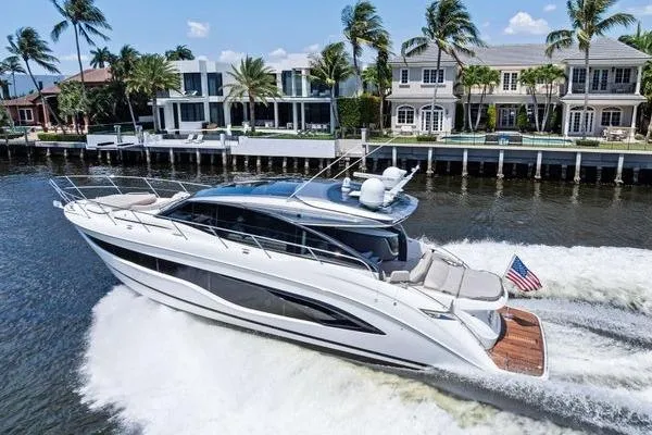 Slide: The Image of 2020 Princess V55 yacht cruising near luxury waterfront homes with palm trees. - 2