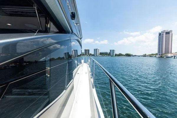 Slide: The Image of 2020 Princess V55 yacht cruising on a sunny day with city skyline in the background. - 8