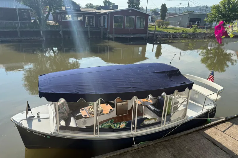 Slide: The Image of 2021 Duffy Sun Cruiser 22 docked by a calm river with a blue canopy. - 4