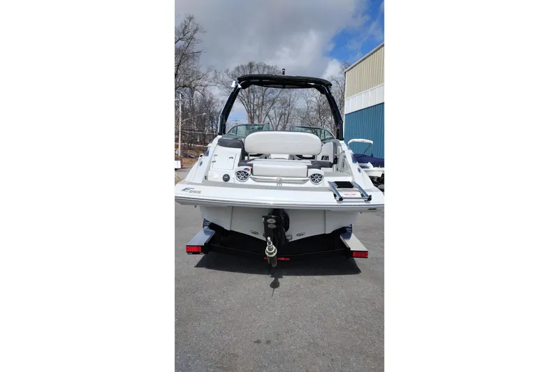 Slide: The Image of 2026 Crownline Eclipse E255 boat rear view, parked outdoors under cloudy sky. - 26