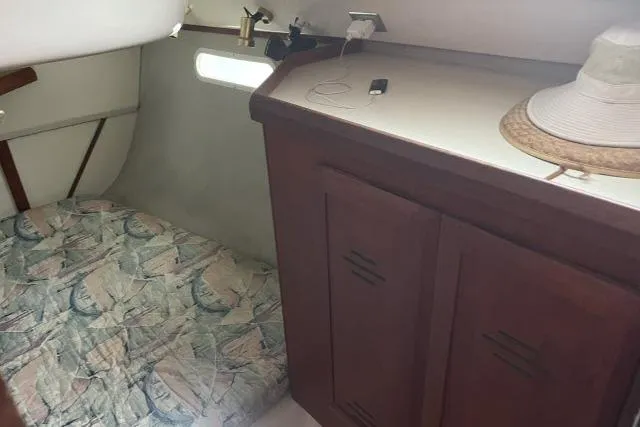Slide: The Image of 1995 Hunter 336 yacht interior with bed, wooden cabinet, and hat on counter. - 11
